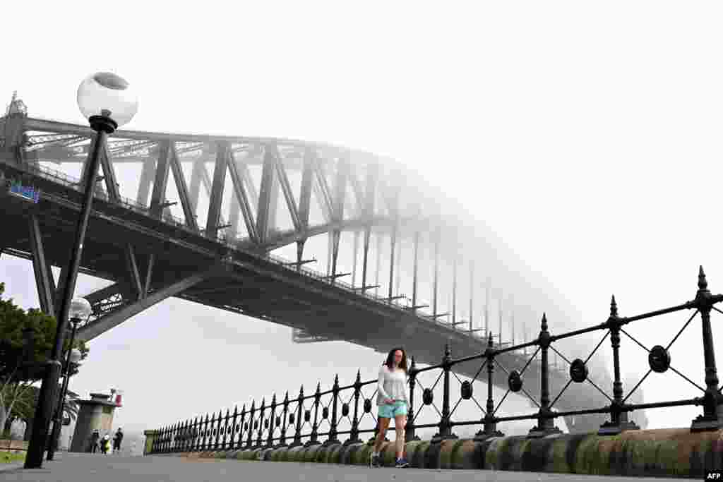 ប្រជាជន​ដើរ​កាត់​ស្ពាន​អូស្រ្តាលី Harbour Bridge ក្នុង​ទីក្រុង​ស៊ីដនី​ខណ​ដែល​ទីក្រុង​នេះ​ត្រូវ​បាន​គ្របដណ្តប់​ដោយ​អាប់​ក្រាស់។