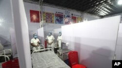 FILE - Nurses from the Tata Memorial Hospital stand inside a temporary facility created to screen cancer patients for COVID-19 in Mumbai, India, July 30, 2020.