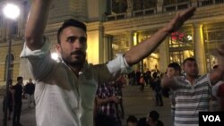 A Syrian man organizes a sit-in outside Budapest's East railway station Friday night as thousands of stranded migrants await passage to Austria, and ultimately Germany, Sept. 4, 2014. (VOA / L. Ramirez)
