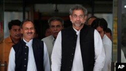 PM interim Pakistan, Shahid Khaqan Abbasi, kanan, bersama pembantunya meninggalkan gedung Parlemen setelah bertemu dengan para politisi di Islamabad, Pakistan, 31 Juli 2017.