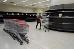 A woman walks past empty shelves at a supermarket in Hong Kong, Feb. 7, 2020. Residents have been buying large amounts of products because they fear that border restrictions, enforced to control the coronavirus outbreak, may affect supply flows.