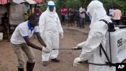Des agents de santé venant de prendre un échantillon de sang d'un enfant à tester pour le virus Ebola dans une zone où un garçon de 17 ans est mort du virus en périphérie de Monrovia, au Libéria, 30 juin 2015. (AP Photo/ Abbas Dulleh,File)