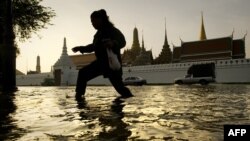 Seorang perempuan berjalan mengarungi banjir, yang diakibatkan musim monsun, di depan Istana Agung dekat Sungai Chao Praya, 28 Oktober 2011.
