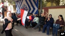 Para pemilih menyanyikan lagu-lagu nasional ketika mereka bersiap untuk memasuki TPS pada hari pertama pemilihan presiden di Kairo, 26 Maret 2018.