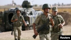 Turkish soldiers walk stand guard on the Turkish-Syrian border near the Akcakale border crossing, southern Sanliurfa province, October 5, 2012. 