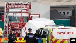 Police officers are on the scene after a truck, in rear, was found to contain a 39 dead bodies, in Thurrock, England, Oct. 23, 2019. 