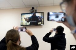 Wartawan mengambil gambar ketika pemimpin oposisi Rusia Alexei Navalny melihat ke kamera saat berbicara dari penjara melalui tautan video, di Petushki, wilayah Vladimir, sekitar 120 kilometer timur Moskow, Rusia, Senin, 17 Januari 2022. (Foto: AP )