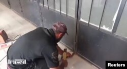 تظاهرکننده‌ای در ورودی شعبه محلی اتحادیه کشاورزان در شهر السویدا سوریه را جوش می‌دهند - ۱۷ شهریور ۱۴۰۲