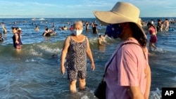 Women wearing face masks stand on a beach in Vung Tau city, Vietnam, July 26, 2020. 