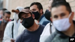 Workers wearing face masks amid the new coronavirus line up to enter the Corabastos market, one of Latin America's largest food distribution centers in the Kennedy area of Bogota, Colombia, June 1, 2020. 