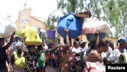 Des Togolaises avec des bagages sur la tête attendent de se faire enregistrer comme réfugiées au village voisin de Hilacondji, Bénin, 2 mai 2005.