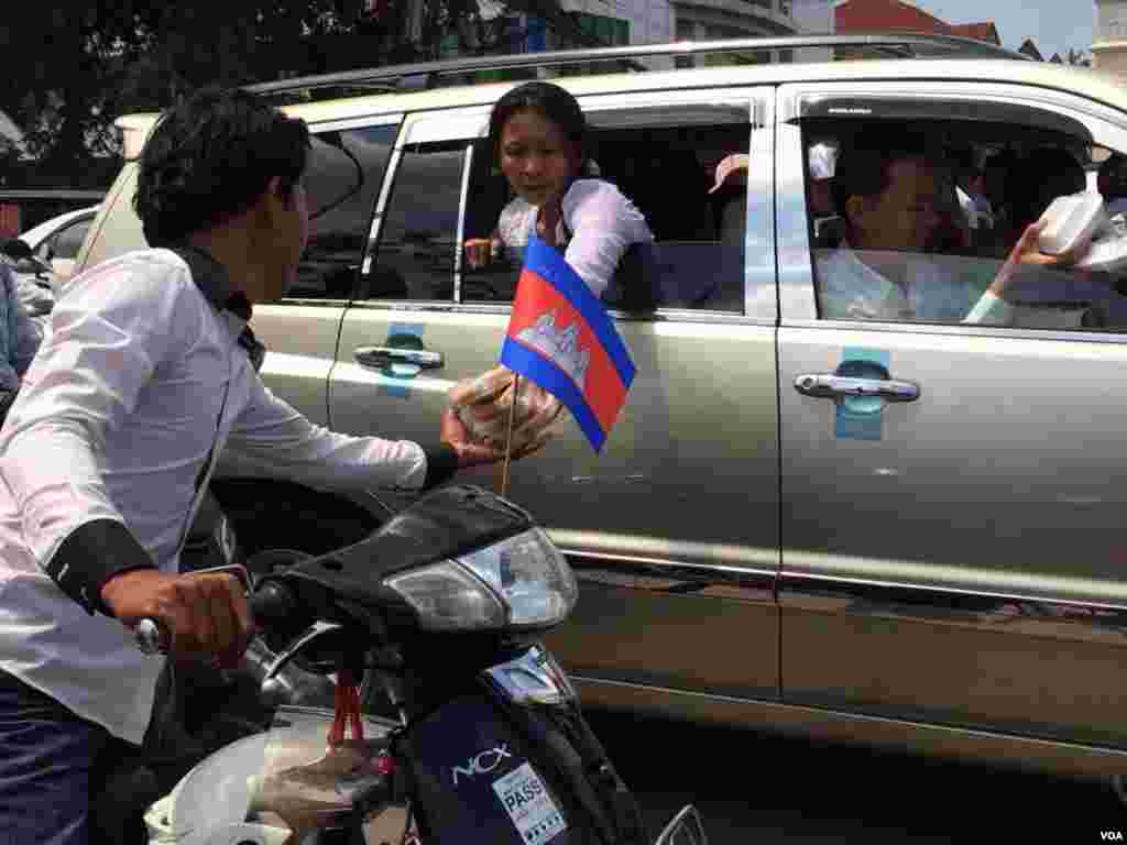 អ្នក​ចូលរួម​រំលែកទុក្ខ​​ចែក​អាហារ​ឲ្យ​ទៅ​អ្នក​ដទៃ​ទៀត​ ដែល​បាន​ចូលរួម​នៅ​ក្នុង​ពិធី​ដង្ហែ​សព​លោក ​កែម ឡី​ ទៅ​កាន់​ខេត្ត​តាកែវ នា​ថ្ងៃ​អាទិត្យ ទី​២៤ ខែ​កក្កដា ឆ្នាំ​២០១៦។ (ផន បុប្ឆា/VOA)