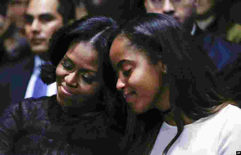 Ibu negara Michelle Obama dan putrinya Malia Obama mendengarkan Presiden Barack Obama menyampaikan pidato perpisahan di McCormick Place di Chicago (10/1). (AP/Pablo Martinez Monsivais)