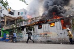 Firefighters run to a restaurant that was set on fire during a protest in Port-au-Prince, Haiti, Sept. 27, 2019.