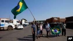 Para sopir truk mengibarkan bendera saat melakukan aksi mogok untuk mendukung pemerintahan Presiden Bolsonaro di Brasilia, Brazil, Kamis (9/9). 