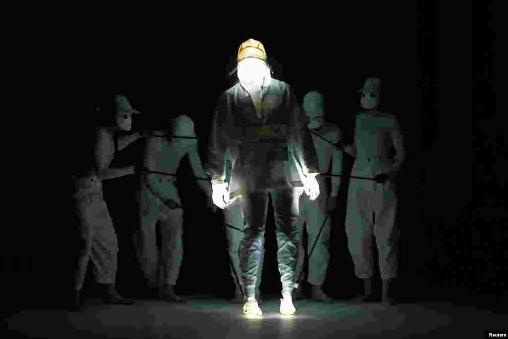 Puppeteers perform with a puppet model which is presenting a creation at the Aitor Throup catwalk show in London, Britain on June 12, 2016.