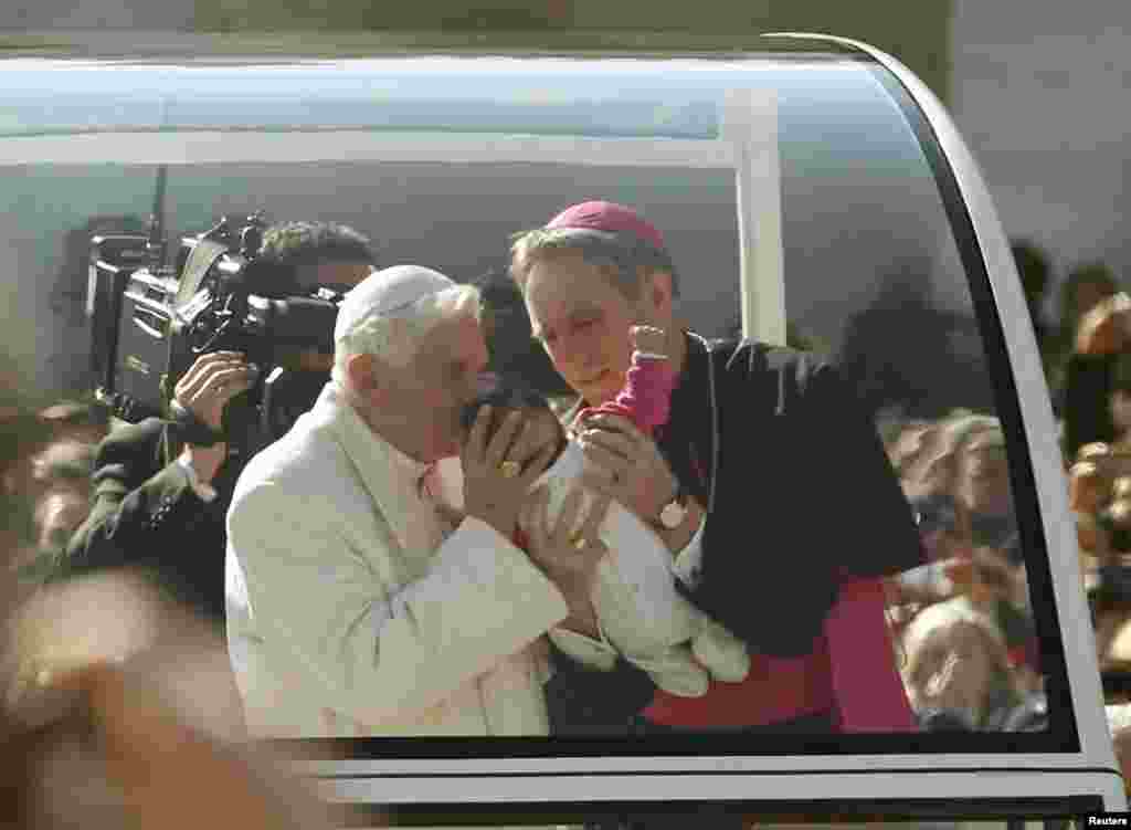 Pope Benedict blesses a baby as he rides around St. Peter&#39;s Square to hold his last general audience at the Vatican Feb. 27, 2013. 