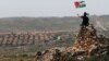 A protester waves a Palestinian flag in front of the Jewish settlement of Ofra during clashes near the West Bank village of Deir Jarir near Ramallah Apr. 26, 2013.