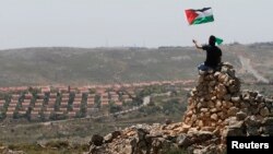 Seorang demonstran melambaikan bendera Palestina di dekat permukiman Yahudi Ofra di dekat Ramallah, Tepi Barat (foto: dok). Liga Arab mengusulkan pertukaran lahan untuk sengketa perbatasan Israel-Palestina. 