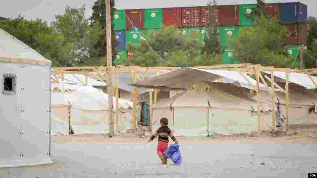 A child walks through Schisto camp, one of around 50 refugee camps scattered around Greece. (J. Owens for VOA)