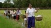 A Cambodian woman, foreground, carries baskets loaded with food together with her neighbors as they walk through rice paddy fields after a Buddhist ceremony locally called Bonn Kathen at Prey Thom village, Takeo province, about 80 kilometers (50 miles) south of Phnom Penh, Cambodia, Sunday, Nov. 6, 2011. (AP Photo/Heng Sinith)