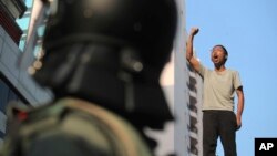 지난 18일 홍콩 시위대의 마지막 거점인 홍콩이공대에 경찰이 진입한 후 한 시위 참가자가 다리 위에서 시위 구호를 외치고 있다.