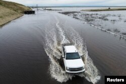 A truck passes on a road as floodwaters from the Tule River inundate the area after days of heavy rain in Corcoran, California, U.S. on March 22, 2023. (REUTERS/David Swanson)