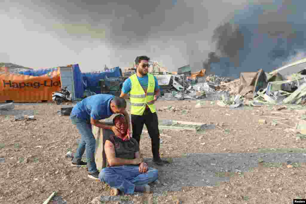 An injured man is helped at the site of an explosion in Beirut, Lebanon, Aug. 4, 2020.