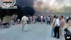 People gather in a street in Hama as smoke rises in the background in this video image posted on a social media website on August 2, 2011 (the authenticity of the video from which this image was taken cannot be independently verified)