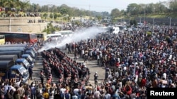 FILE - Police fire a water cannon at protesters demonstrating against the military coup and demanding the release of elected leader Aung San Suu Kyi, in Naypyitaw, Myanmar, on Feb. 8, 2021.