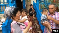 A Uyghur man and woman hold young Uyghur children in Xinjiang, China (VOA) 