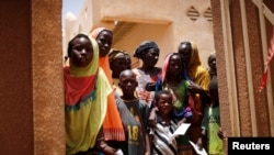 FILE - Local women and children arrive at an abandoned clinic to receive medical care from the French military during Operation Barkhane in Ndaki, Mali, July 29, 2019. 
