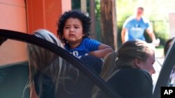A child from Honduras is brought to the U,S. Immigration and Customs Enforcement office in Grand Rapids, Mich., July 10, 2018. Two boys and a girl who had been in temporary foster care in Grand Rapids were reunited with their Honduran fathers after they were separated at the U.S.-Mexico border about three months ago. 