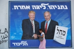 A woman walks past a Likud party election campaign banner depicting Israeli Prime Minister Benjamin Netanyahu and U.S. President Donald Trump in Tel Aviv, Israel, Sept. 16, 2019.