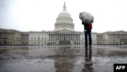 Seorang turis membawa payung di tengah hujan salju yang melanda Washington DC hari Rabu (6/3). 