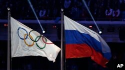 FILE - In this Feb. 23, 2014, photo, the Russian national flag, right, flies next to the Olympic flag during the closing ceremony of the 2014 Winter Olympics in Sochi, Russia.