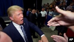 FILE - FILE - In this Aug. 11, 2015, file photo, Republican presidential candidate Donald Trump meets supporters after addressing a GOP fundraising event in Birch Run, Mich.