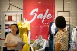 People walk past a store advertising a sale in a shopping mall in Beijing, Aug. 2, 2019.