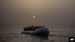 FILE - African refugees and migrants wait for assistance aboard a rubber boat, off the Libyan coast, Feb. 23, 2017.
