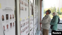 Para pemilih mengenakan asker memeriksa papan informasi di luar tempat pemilihan suara (TPS) dalam pemilu daerah di tengah pandemi virus corona (COVID-19) di Kyiv, Ukraina, 25 Oktober 2020. 