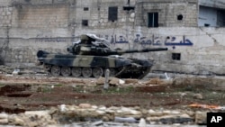 Tank tentara Suriah di depan dinding bertuliskan "Aleppo adalah ibukota budaya" di Tariq al-Bab, Aleppo timur (3/12). (AP/Hassan Ammar)