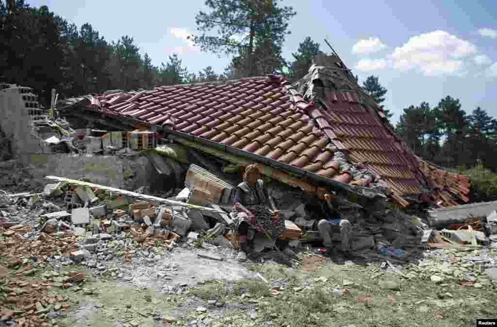 A Bulgarian Roma woman sits in front of her house after it was demolished in a Roma suburb in the city of Stara Zagora. Municipal authorities started demolishing some 55 illegally built shacks and houses in the suburb.