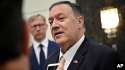 FILE - Then-Secretary of State Mike Pompeo speaks to the media before departing from al-Bateen Air Base in Abu Dhabi, United Arab Emirates, on Sept. 19, 2019, as U.S. special Iran envoy Brian Hook, left, listens. 