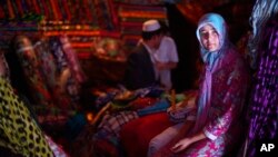 A Uyghur girl looks out from a textile shop in the town's market Bazaar in the city of Hotan, China, Wednesday July 15, 2009. (AP Photo/Elizabeth Dalziel)