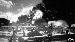 Para pelaut berdiri di antara pesawat yang hancur di Pangkalan Udara Angkatan Laut Amerika Ford Island, saat berlangsungnya serangan Jepang di Pearl Harbor, Hawaii 7 Desember 1941 (foto: dok).