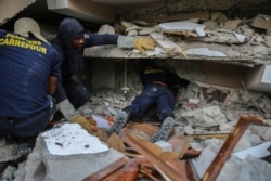 Firefighters search for survivors inside a collapsed building, after Saturday´s 7.2 magnitude earthquake in Les Cayes, Haiti, Aug. 15, 2021.