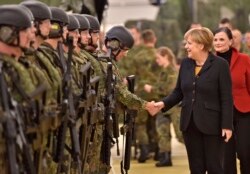 FILE - German chancellor Angela Merkel shakes hands with soldiers during a visit of the German Army medical service in Leer, northern Germany, Dec. 7, 2015.