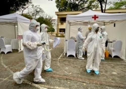 FILE - Health workers walk through the grounds at a makeshift COVID-19 testing facility in Hanoi, Vietnam, Mar. 31, 2020.