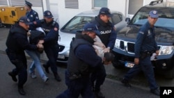 FILE - Montenegrin police officers escort people suspected of planning armed attacks after the parliamentary vote in Podgorica, Montenegro, Oct. 16, 2016. Prosecutors have accused Russia and its secret service operatives of having plotted a coup attempt that included plans to kill the small Balkan country's then prime minister, Milo Djukanovic.