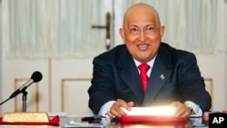 Venezuela's President Hugo Chavez smiles while holding a gold ingot after signing a decree for the nationalization of the gold mining industry, at Miraflores Palace in Caracas August 23, 2011